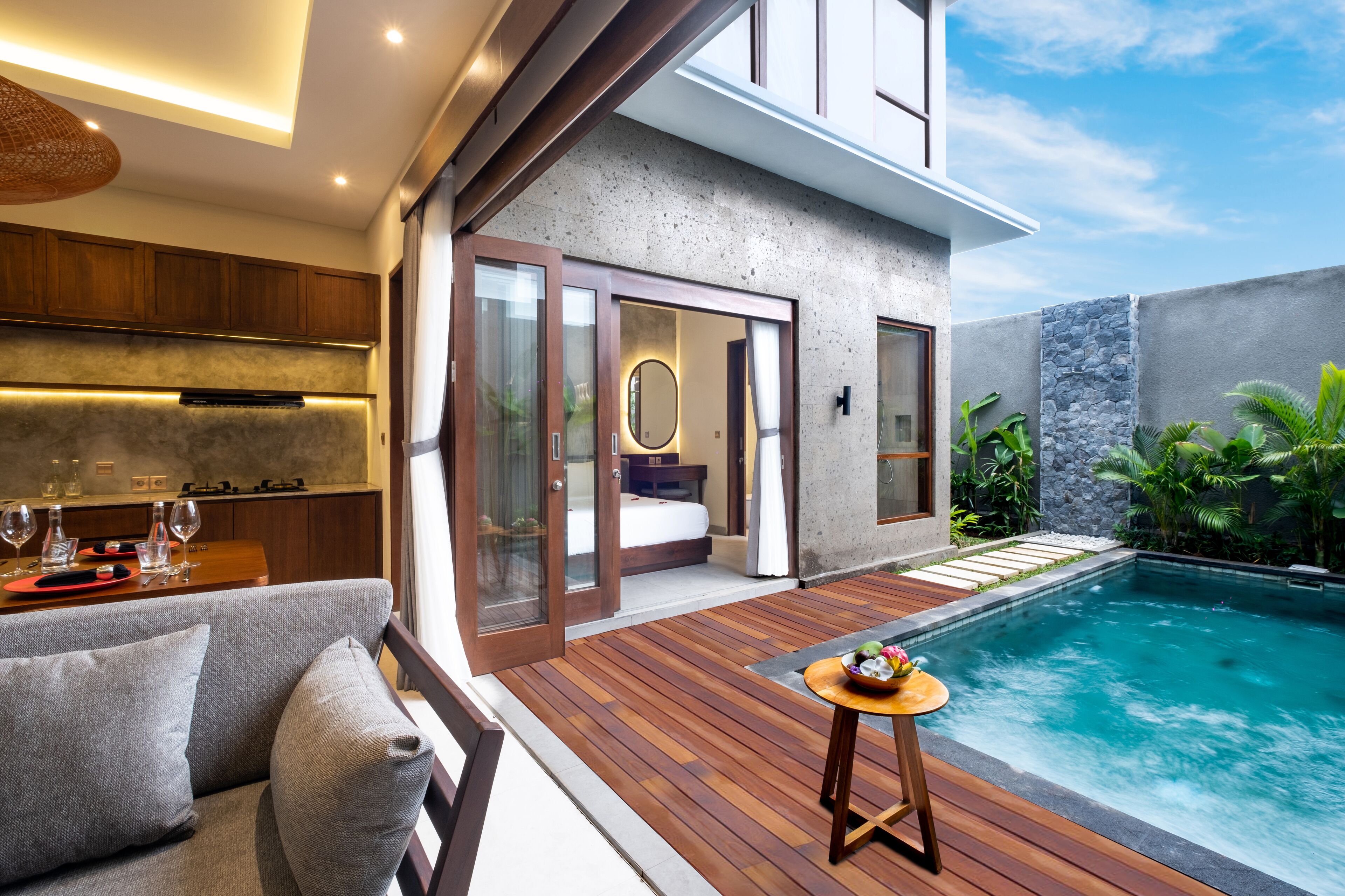 Un espace de vie extérieur moderne comprenant une piscine, une terrasse en bois et un coin salon avec un canapé et une table.
