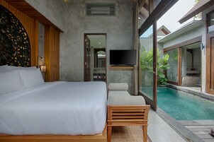 A modern bedroom with a large bed, a TV, and a view of a swimming pool.