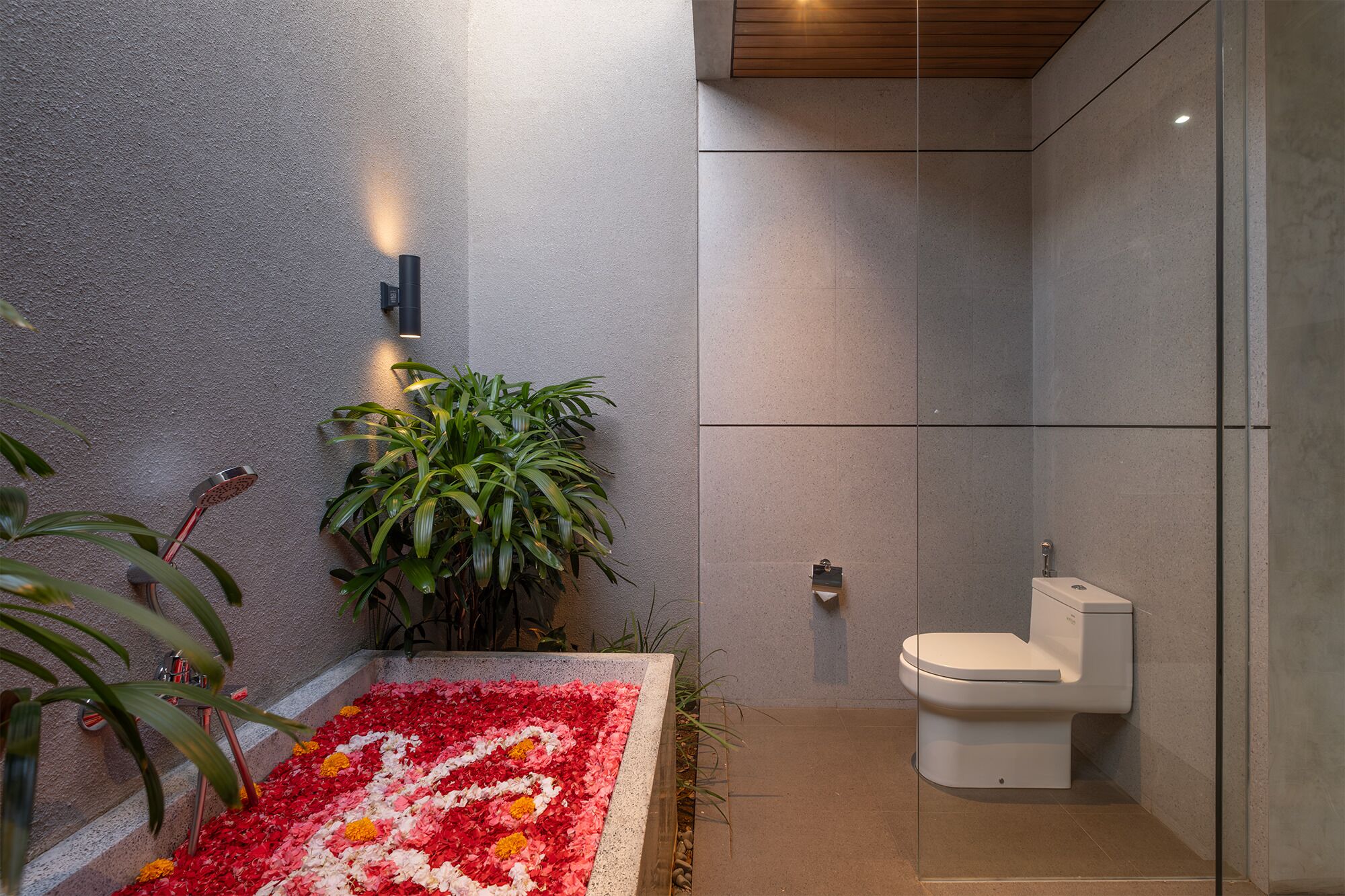 A modern bathroom with a shower, toilet, and a wall-mounted light fixture.