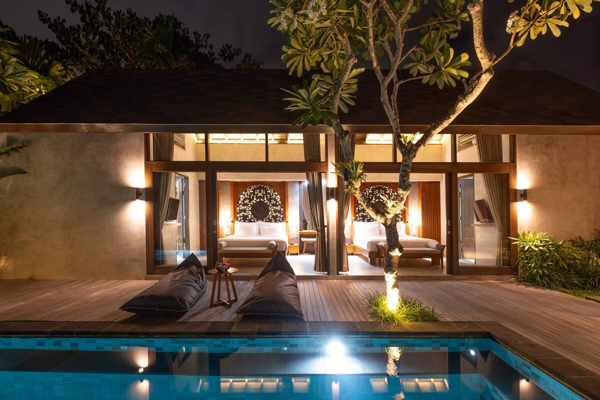 A modern hotel with a pool, a lounge area with sofas, and a well-lit interior.