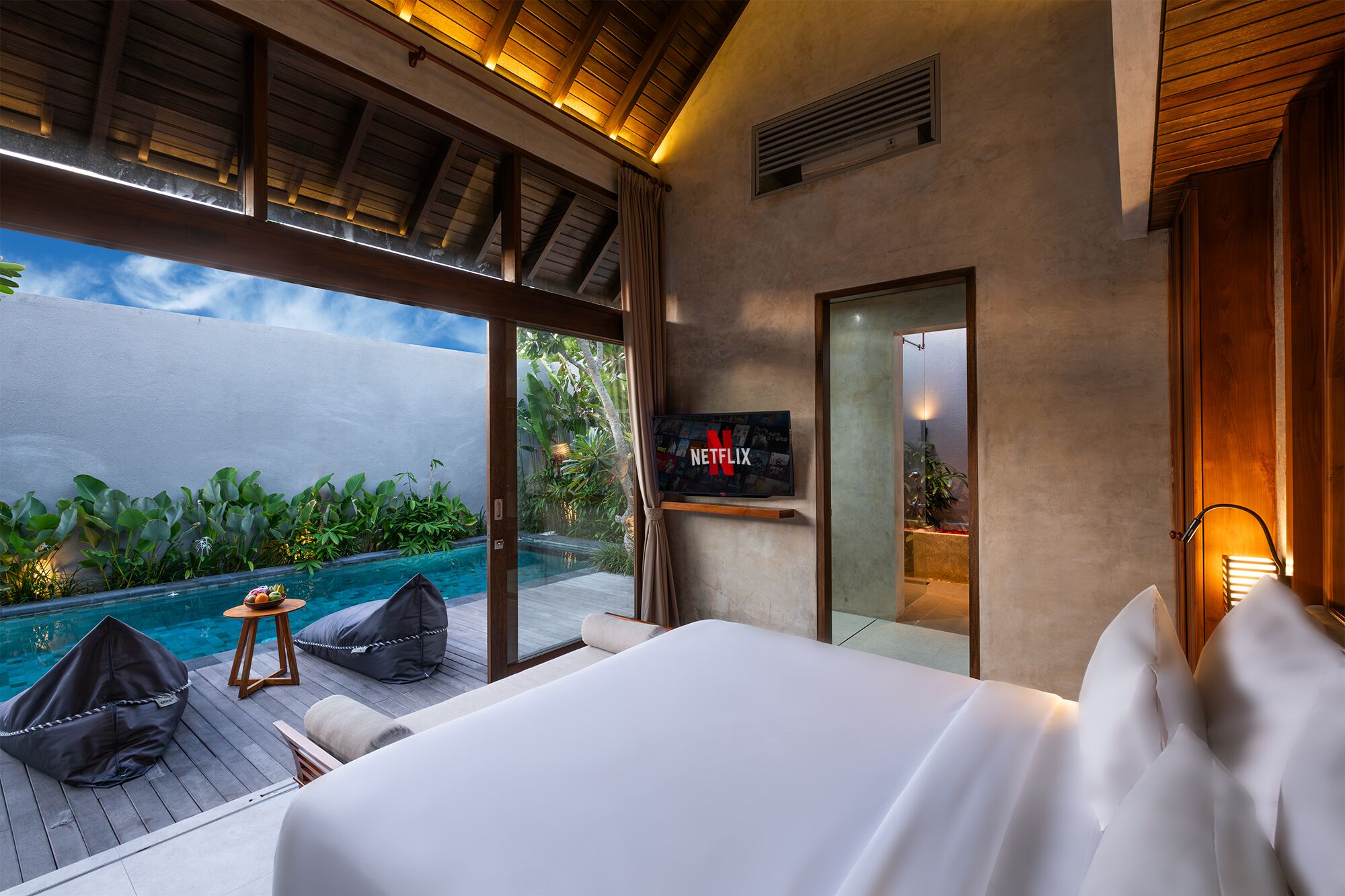 Une chambre avec un grand lit, une télévision et une vue sur une piscine.
