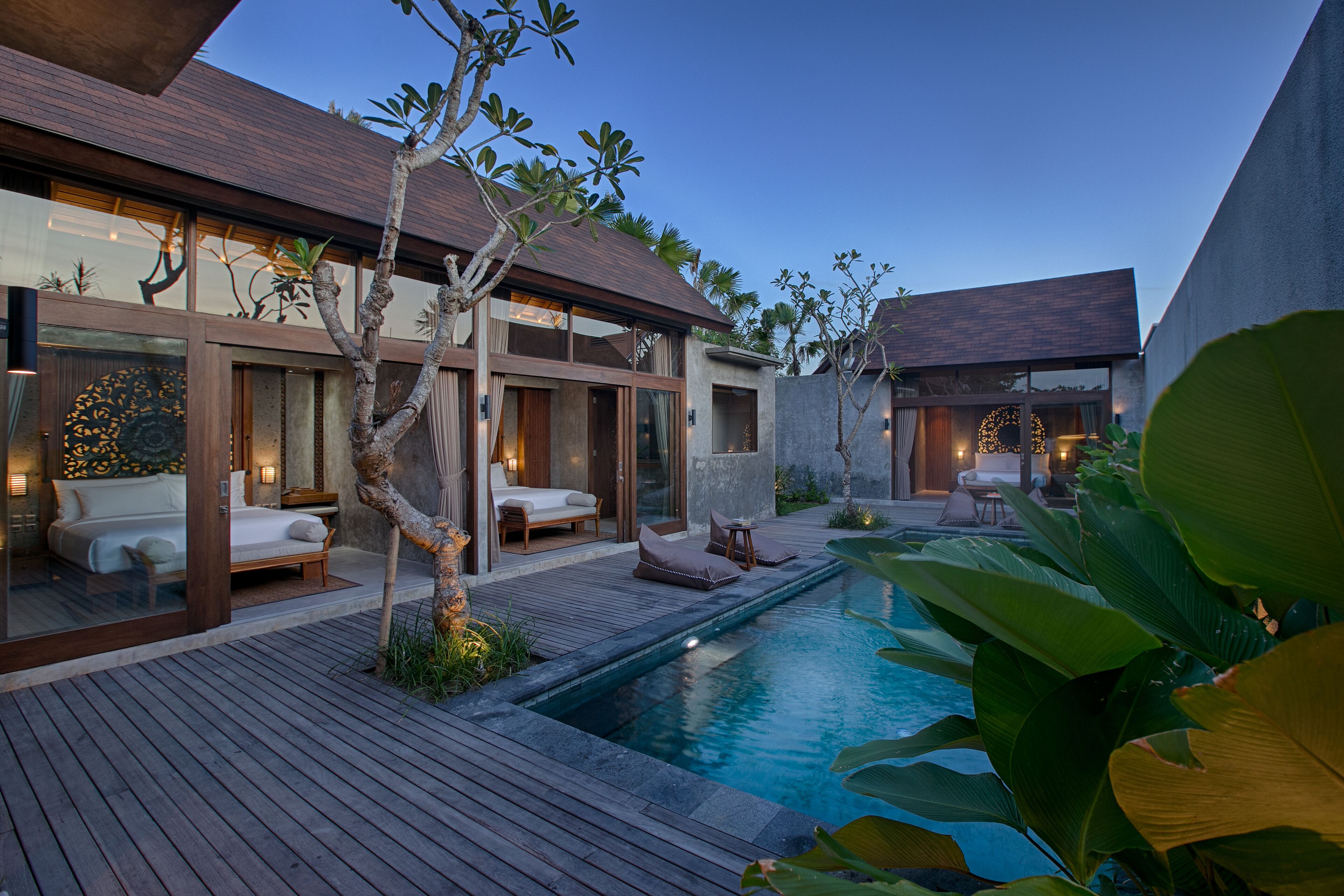 Un moderno resort con piscina, terraza de madera y zonas de estar al aire libre.