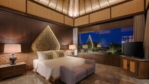 Une chambre à coucher moderne avec un grand lit, une table de chevet, un téléviseur et une vue sur le paysage urbain la nuit.