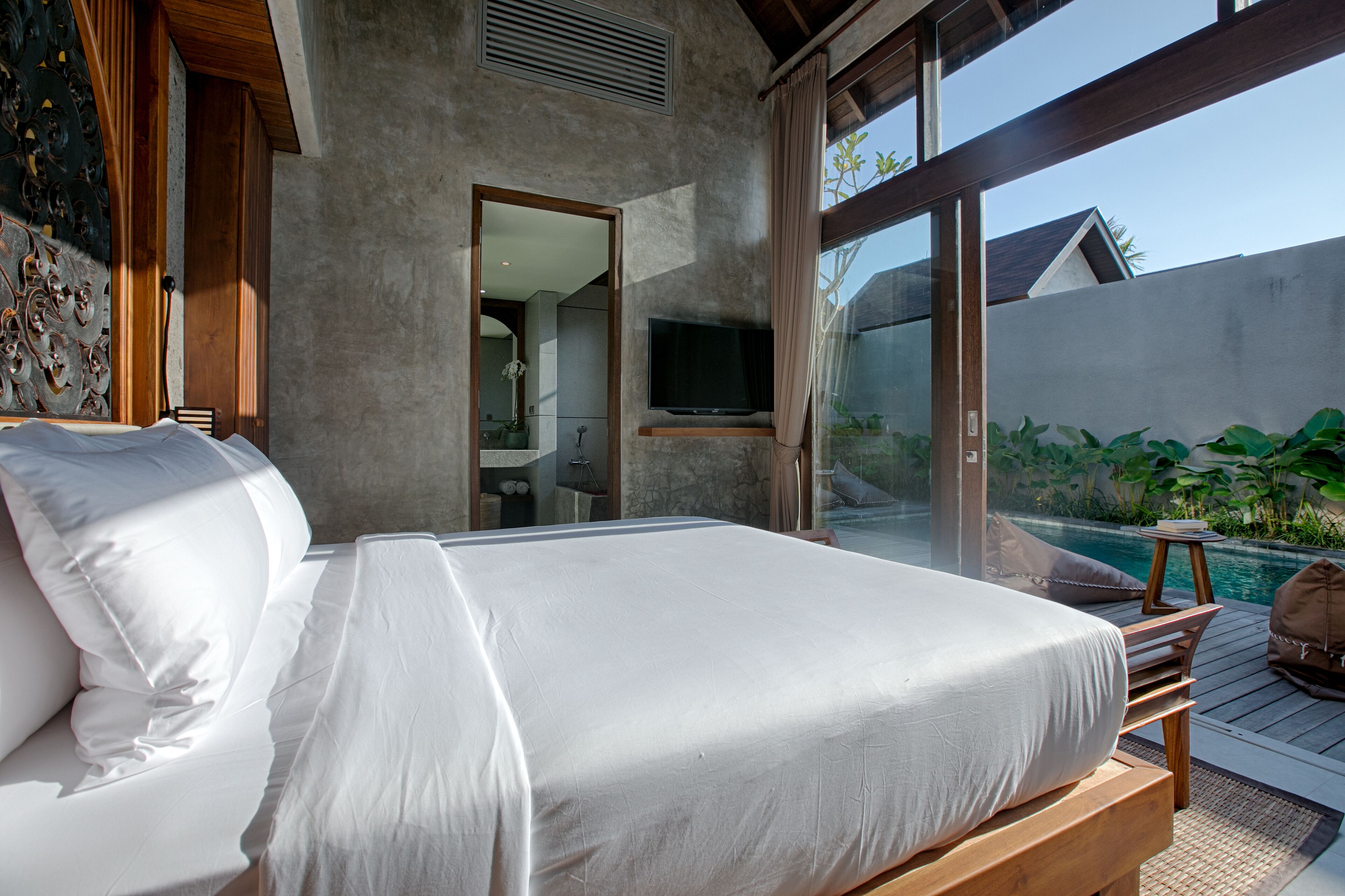 A bedroom with a large bed, a TV, and a view of a swimming pool.