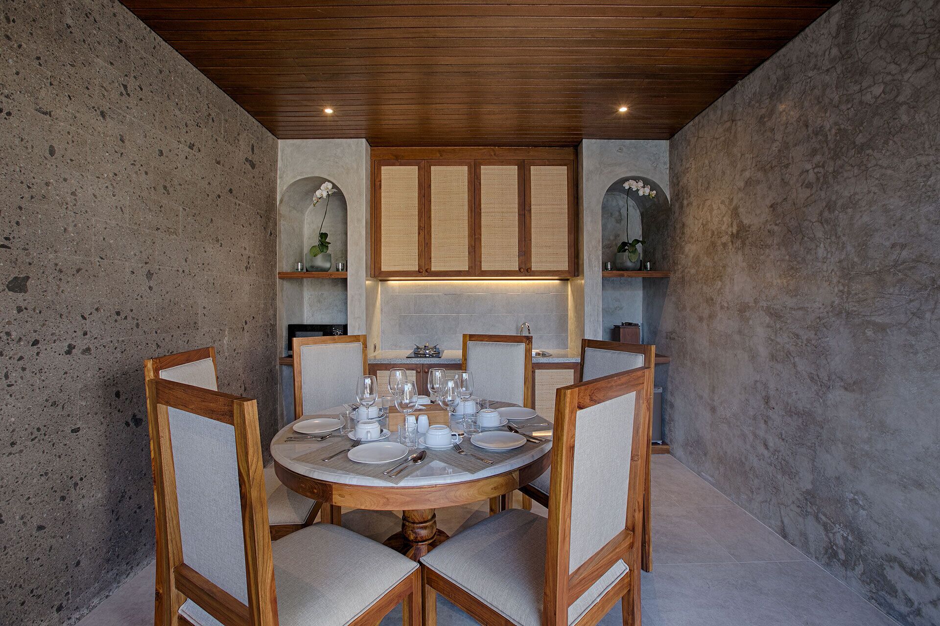 Un coin repas avec une table ronde dressée pour six personnes, entourée de chaises en bois dotées d’assises rembourrées.