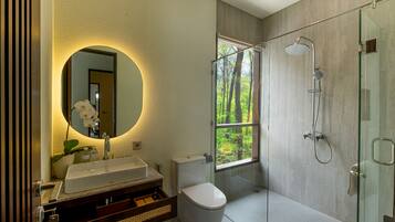 A modern bathroom with a large mirror, a white sink, a toilet, and a glass-enclosed shower.