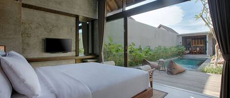 Un dormitorio con una cama grande, un televisor montado en la pared y vistas a una piscina y zona de estar exterior.