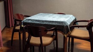 A dining area with a square table covered by a textured tablecloth, surrounded by four wooden chairs with cushioned seats. - Zhenfeng Fangzhou Hotel (Zhenfeng)