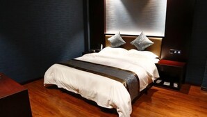 A modern bedroom with a large bed, wooden flooring, and a nightstand with a lamp. - Zhenfeng Fangzhou Hotel (Zhenfeng)