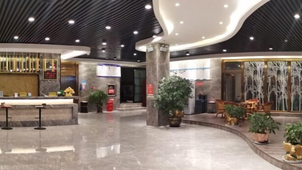 A modern lobby with a marble floor, a reception desk, and seating areas with potted plants. - Zhenfeng Fangzhou Hotel (Zhenfeng)