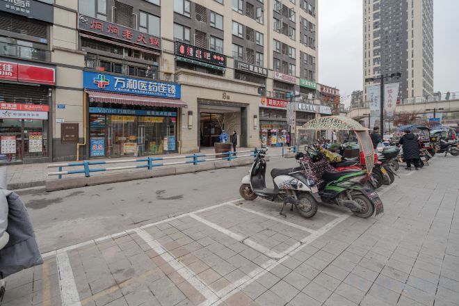 A street with parked scooters and a building with a sign that reads '牛力前瞻医疗集团'.