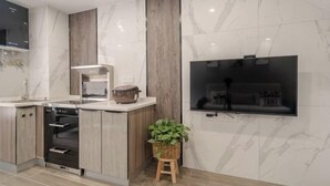 Een moderne keuken met een inbouwoven, een magnetron en een grote televisie aan de muur.