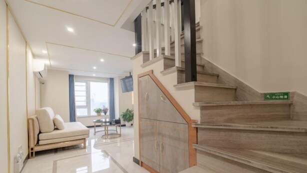 Een moderne woonkamer met een bank, een eettafel en een trap met een houten leuning.