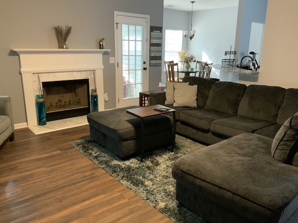 A living room with a fireplace, a sofa, an ottoman, and a rug.