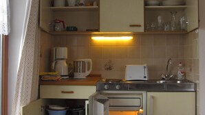 Une cuisine compacte équipée d’un four encastré, d’une machine à café et de divers ustensiles de cuisine disposés sur le plan de travail.