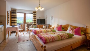 Une chambre confortable avec un lit en bois, un bureau et un téléviseur.