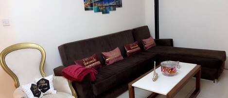 A living room with a dark brown sofa, a gold-framed armchair, and a white coffee table.