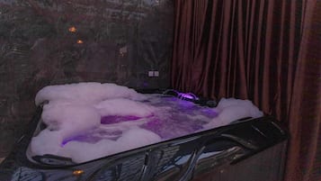 A hot tub with a stone wall and a curtain.