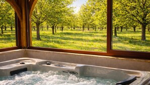 A hot tub with a view of a grassy field and trees through a window. - Quiet Périgord home with jacuzzi & WiFi - 12p (Dordogne)