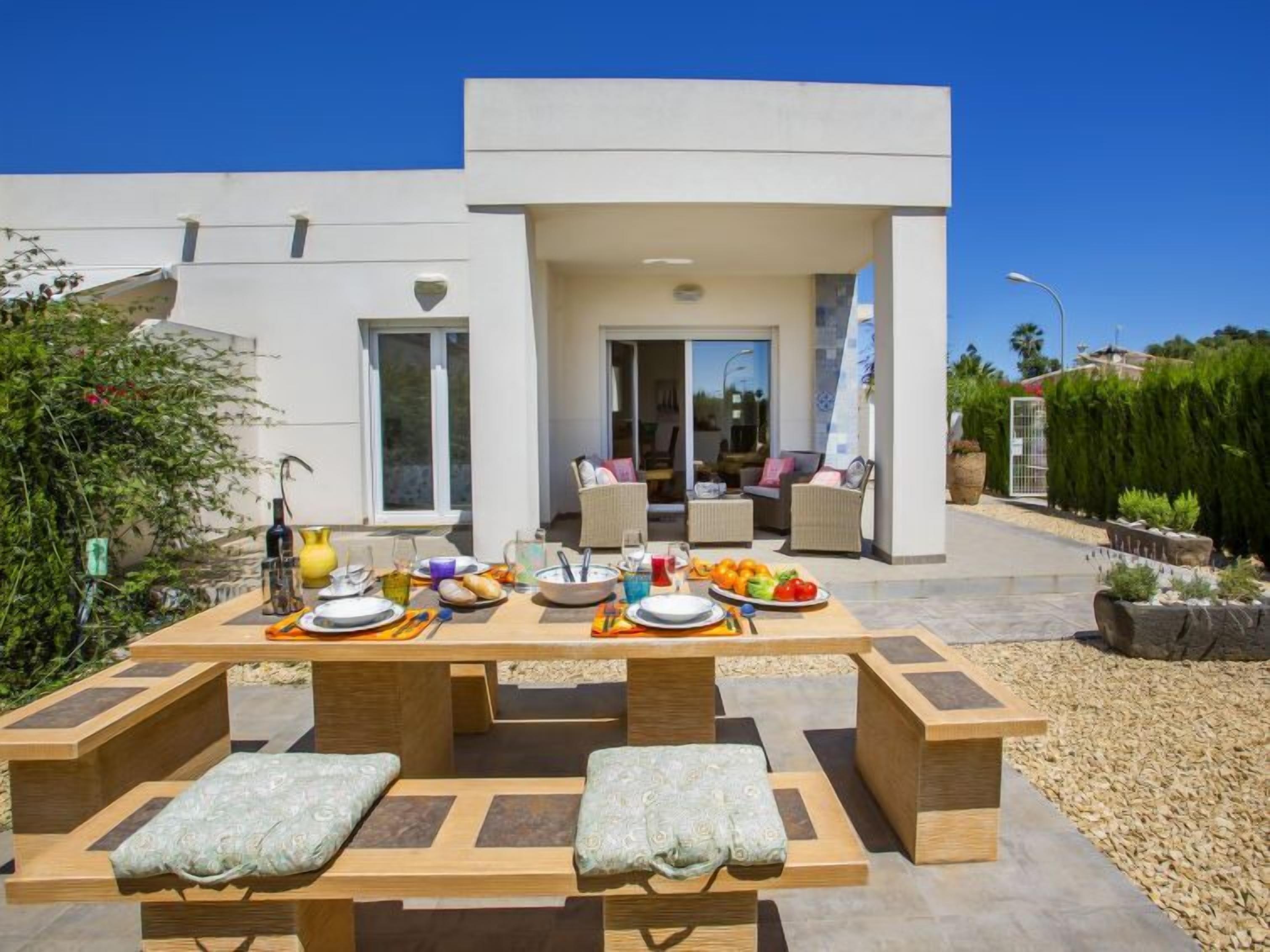 An outdoor dining area with a table set for four, surrounded by cushioned benches.