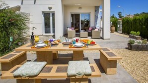 An outdoor dining area with a table set for four, surrounded by cushioned benches. - Casa Jill by Interhome (Dénia)