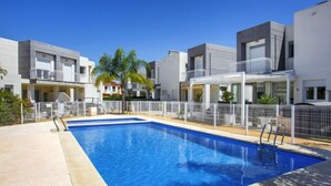 A modern hotel with a rectangular swimming pool, white balconies, and a clear blue sky. - Casa Jill by Interhome (Dénia)