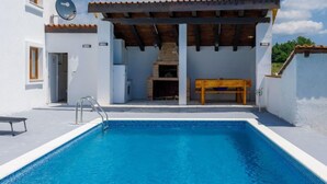 Una piscina con muelle de madera y zona de barbacoa.