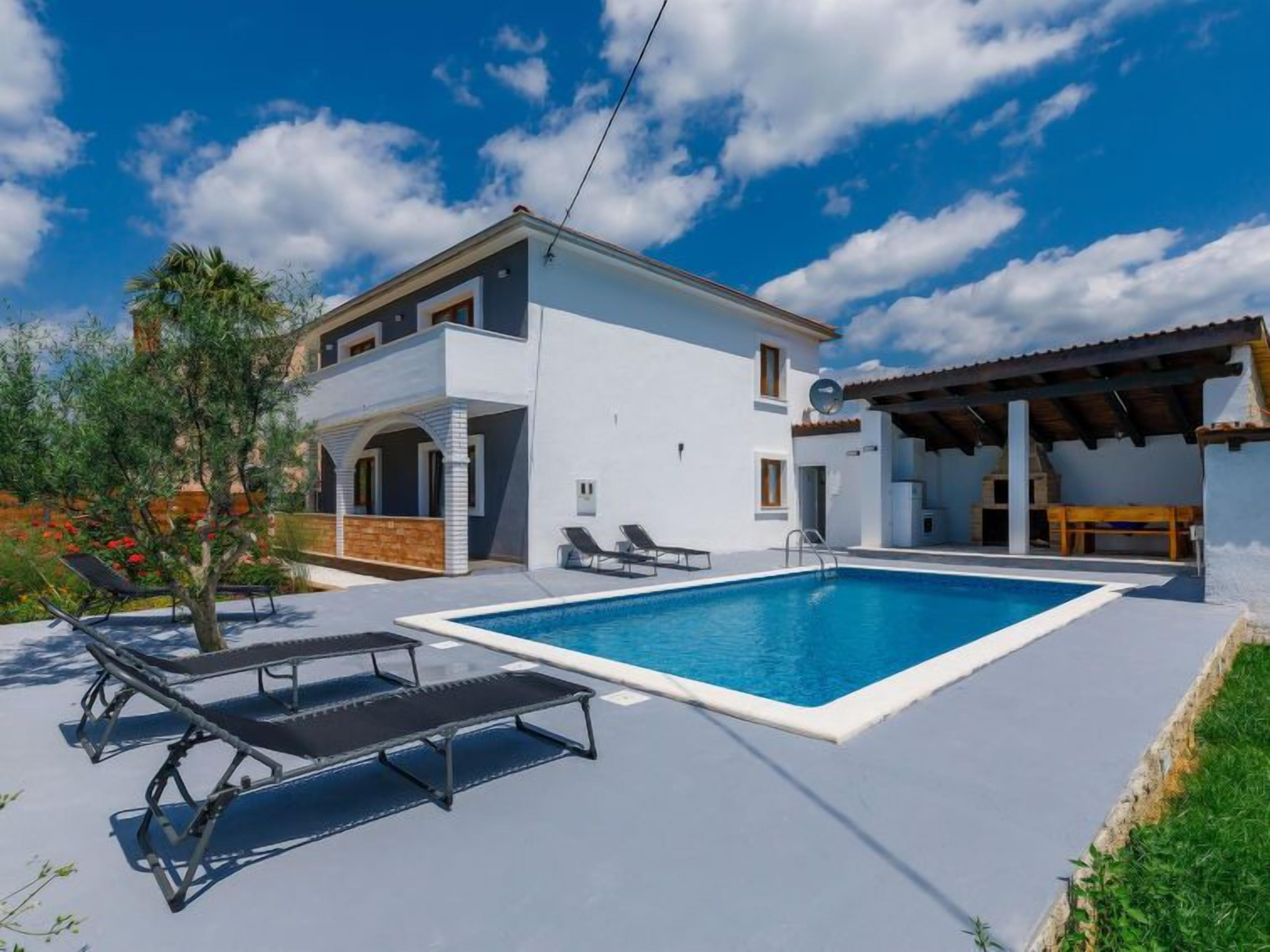 Una casa de dues plantes amb piscina, espai d'exterior per seure i una zona de terrassa coberta.