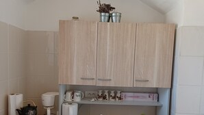Une cuisine avec des meubles de couleur bois clair, un plan de travail sur lequel sont disposés divers ustensiles de cuisine, un évier et une cuisinière.