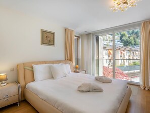 Ein Schlafzimmer mit einem Bett, einem Nachttisch, einer Lampe und einem Fenster mit Vorhängen.