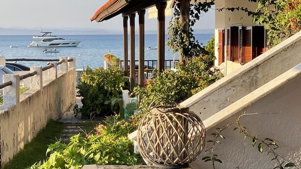 Une propriété située sur la côte, dotée d’un escalier en pierre menant à un balcon offrant une vue sur la mer.