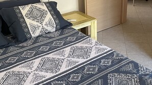 Une chambre à coucher comprenant un lit, une table de chevet, une armoire et un petit tabouret.