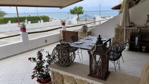 Une terrasse extérieure avec une table dressée pour le repas, entourée de chaises en osier et de plantes en pot.