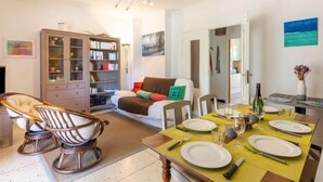 A dining area with a table set for four, a bookshelf, a sofa, and a hanging light fixture. - Le Roumanille by Interhome (Saint Aygulf)