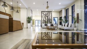 Un moderno hall de entrada con mostrador de recepción, zona de estar y una mesa de centro de cristal.