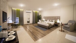 Habitación de hotel moderna con cama, escritorio, silla y una mesita de noche con lámpara.
