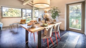 Comedor con una mesa dispuesta para cuatro personas, un ventanal grande y una planta.