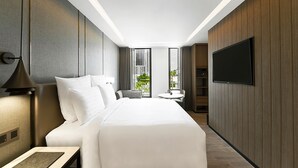 Une chambre d’hôtel moderne dotée d’un grand lit, d’un téléviseur à écran plat, d’un bureau avec un clavier et offrant une vue sur l’extérieur.
