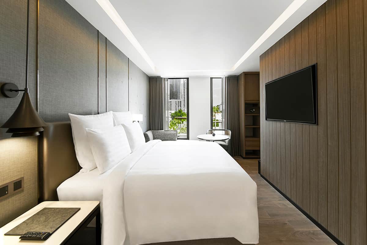 Une chambre d’hôtel moderne dotée d’un grand lit, d’un téléviseur à écran plat, d’un bureau avec un clavier et offrant une vue sur l’extérieur.