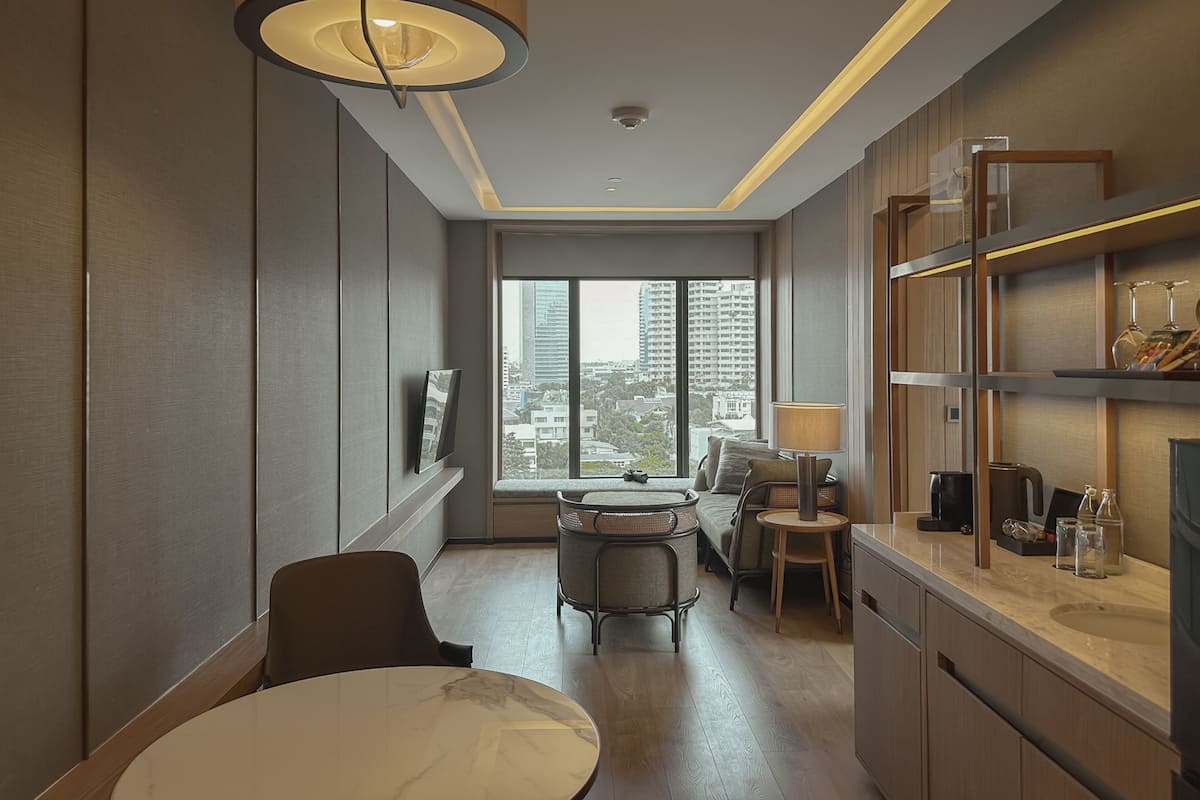 Une chambre d’hôtel moderne dotée d’un coin repas, d’une grande fenêtre offrant une vue sur la ville et d’un espace cuisine.