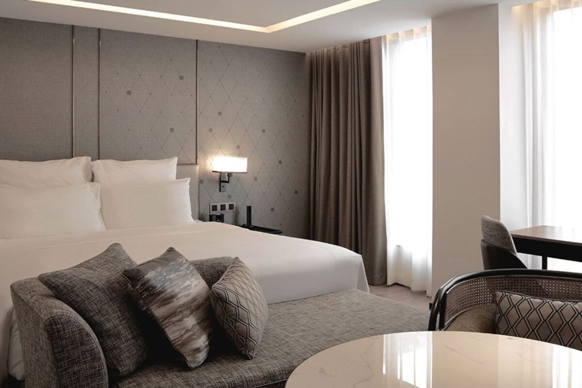 Ein Hotelzimmer mit einem Bett, einer Couch, einem Esstisch und einer Lampe.