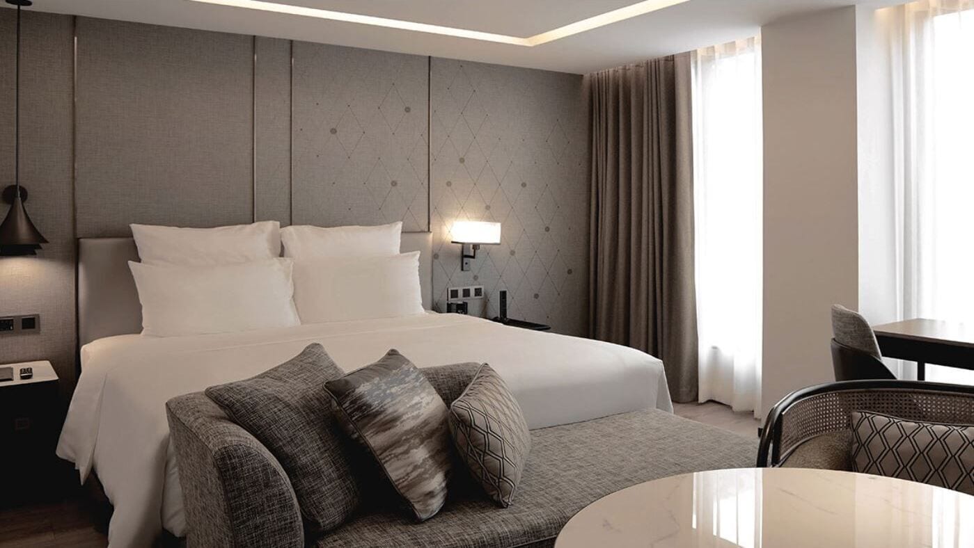 Une chambre d’hôtel avec un lit, un canapé, une table à manger et une lampe.