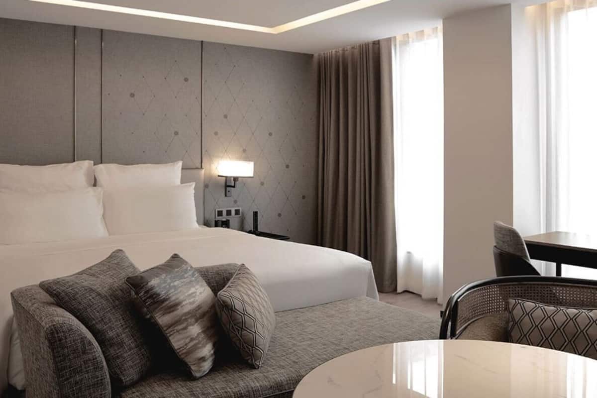 Une chambre d’hôtel avec un lit, un canapé, une table à manger et une lampe.