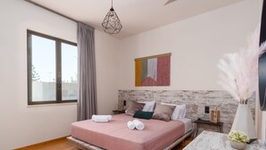 Une chambre moderne avec une grande fenêtre, un lit avec une literie rose, une tête de lit en bois et un élément décoratif mural.
