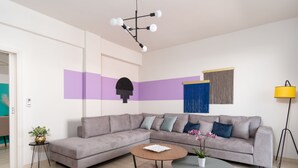 Un salon moderne avec un canapé d’angle gris, une table basse ronde et un lampadaire.