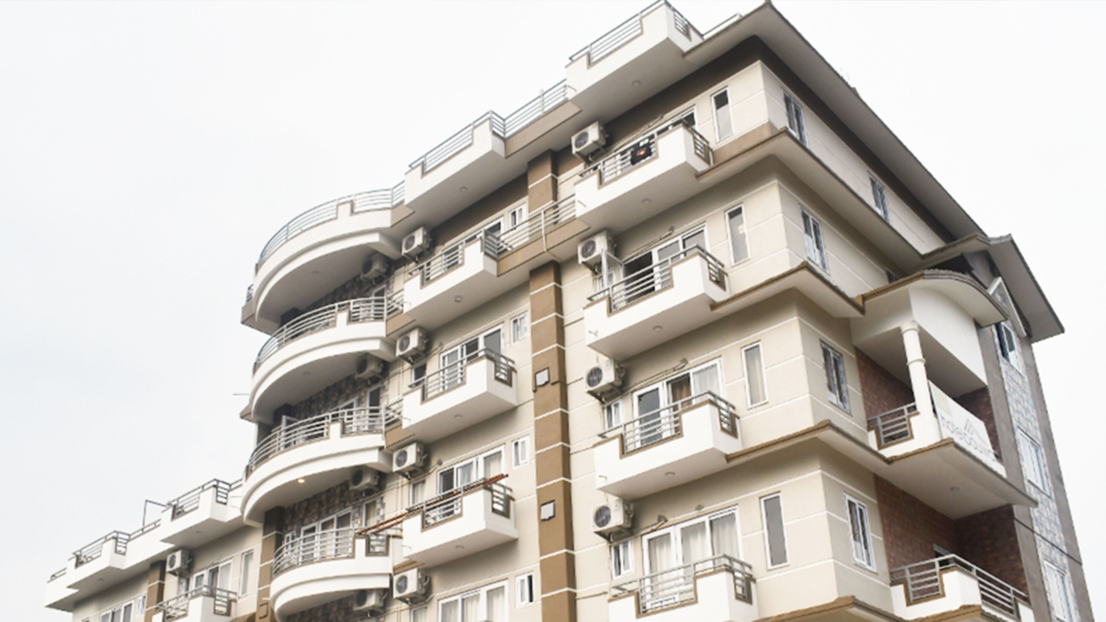 A multi-story residential building with balconies, air conditioning units, and a modern architectural design.