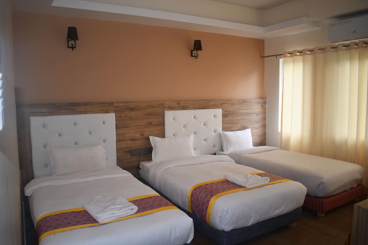 Habitació d'hotel amb dos llits individuals, un capçal de llit de fusta i una finestra amb cortines.