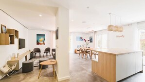 Un salon moderne avec un coin repas, comprenant une table à manger en bois, des chaises et un îlot de cuisine doté d’un plan de travail de couleur claire.
