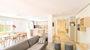 Un salon moderne comprenant un canapé, une table à manger et des chaises. Il y a également un coin cuisine avec des placards et un plan de travail.