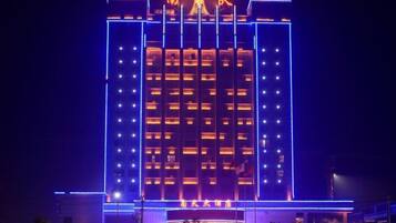 A multi-story hotel with a central tower and illuminated signage.